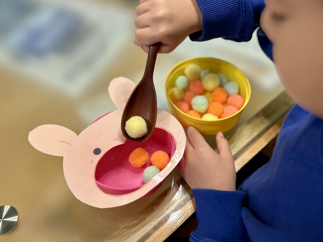 スプーンでボールを移動させる子ども